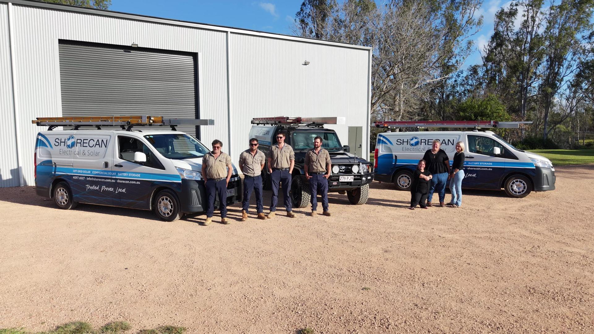 The Shorecan Electrical and Solar team standing together in front of their branded service vehicles at their Ravenshoe workshop